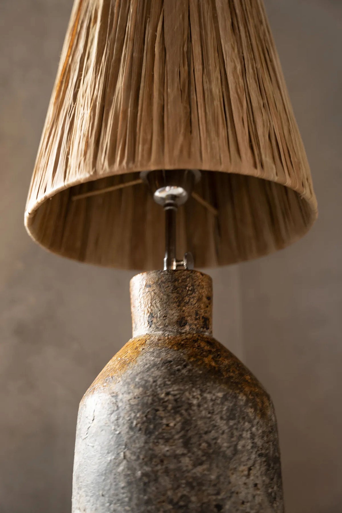 Lamp with a textured base and natural fiber shade against a neutral background