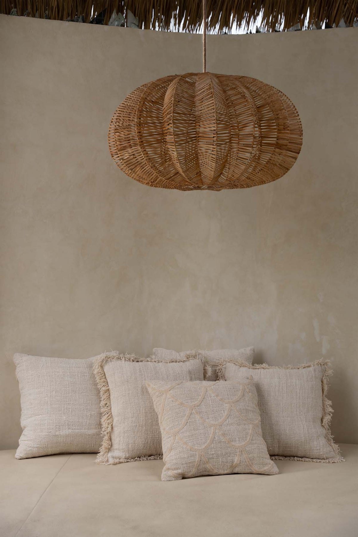 Large oval rattan pendant light against lime washed walls flo & joe uk