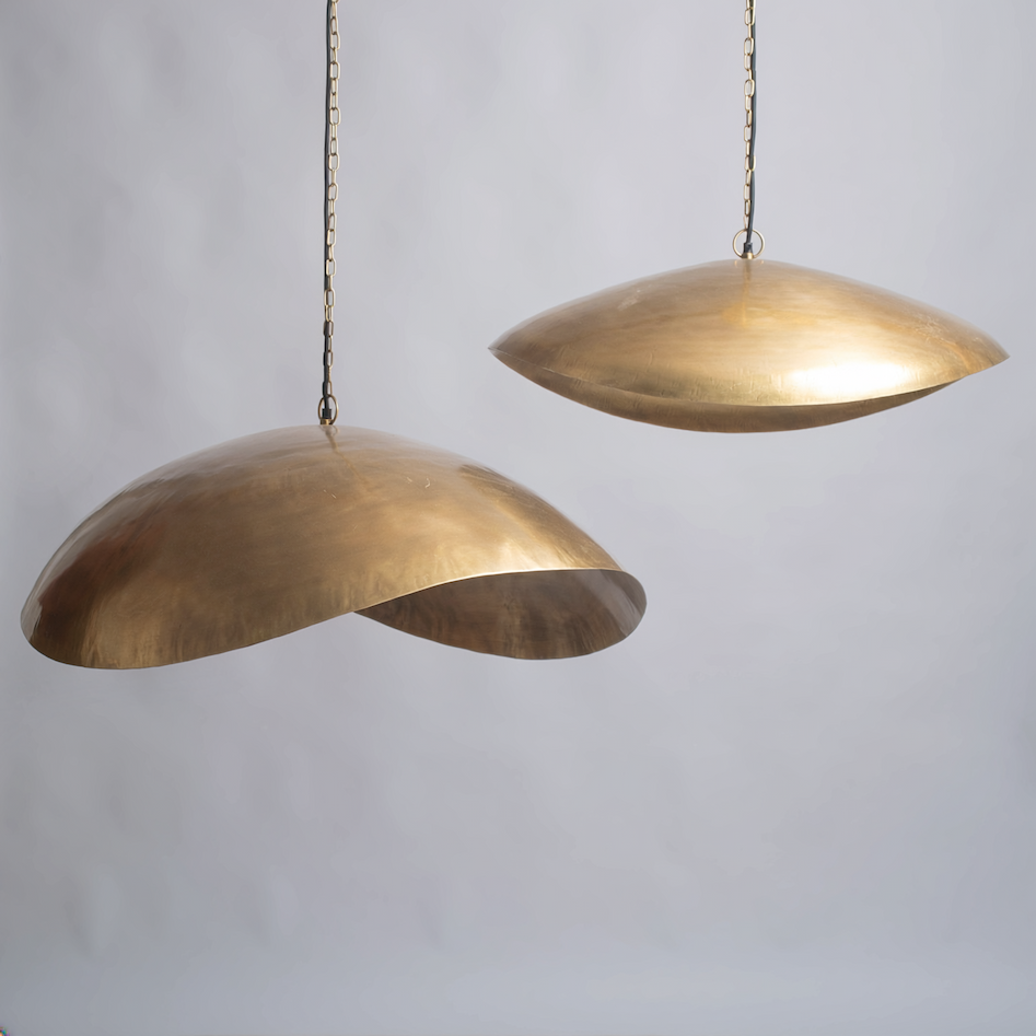 Two brass pendant lights hanging against a plain background