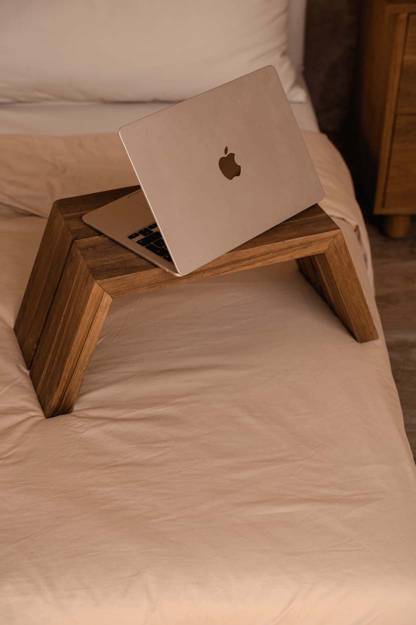 Wooden lap desk with a laptop on a bed