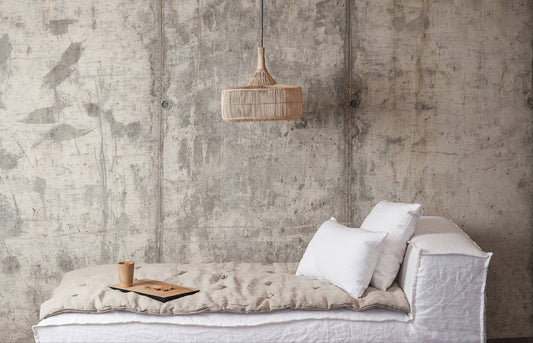 Minimalist interior with a white sofa against a textured concrete wall.