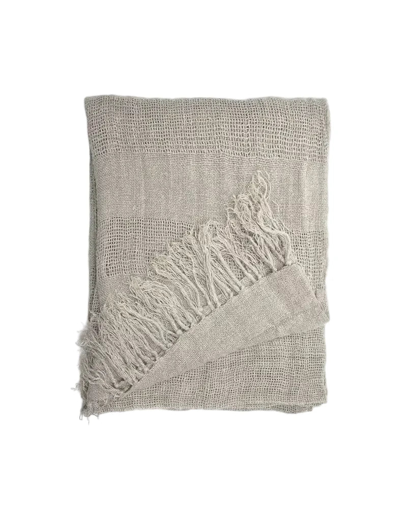 A folded linen curtain panelt in a light taupe beige colour with fringed edges, displayed on a clean white background.