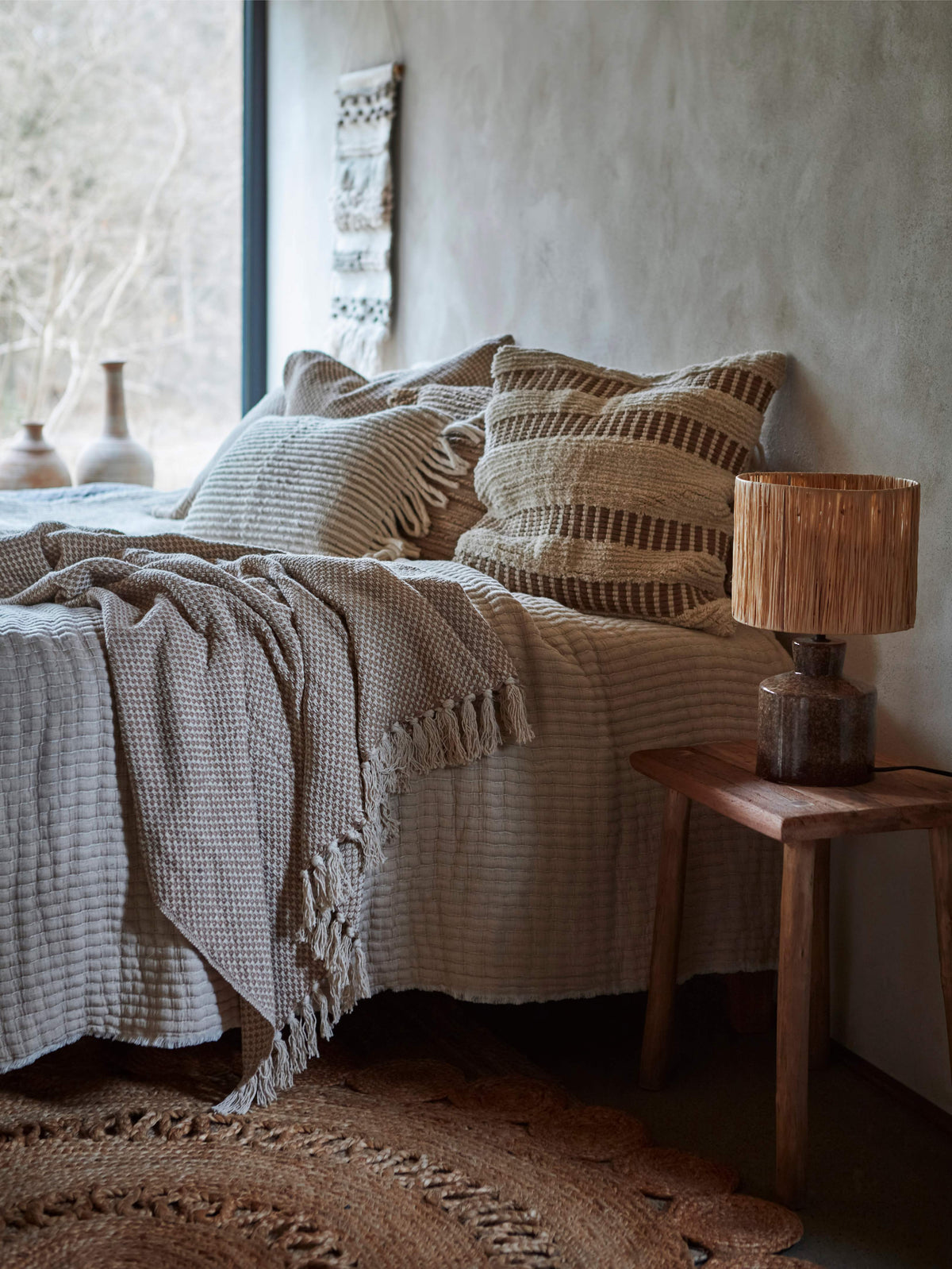 Cozs bedroom with textured bedding and stripe 50cm cushions, wooden nightstand with lamp