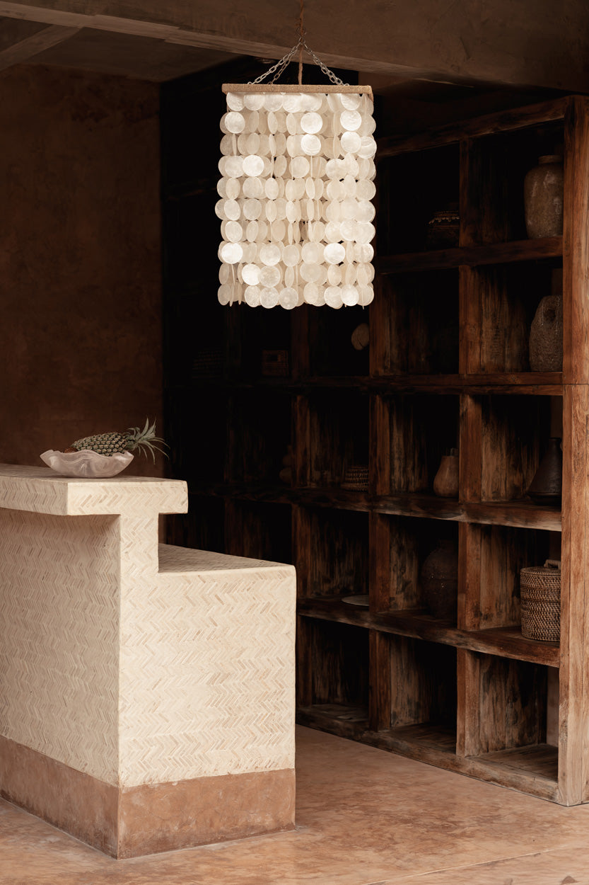 Long hanging shell chandelier hanging in a terracotta rustic kitchen living room
