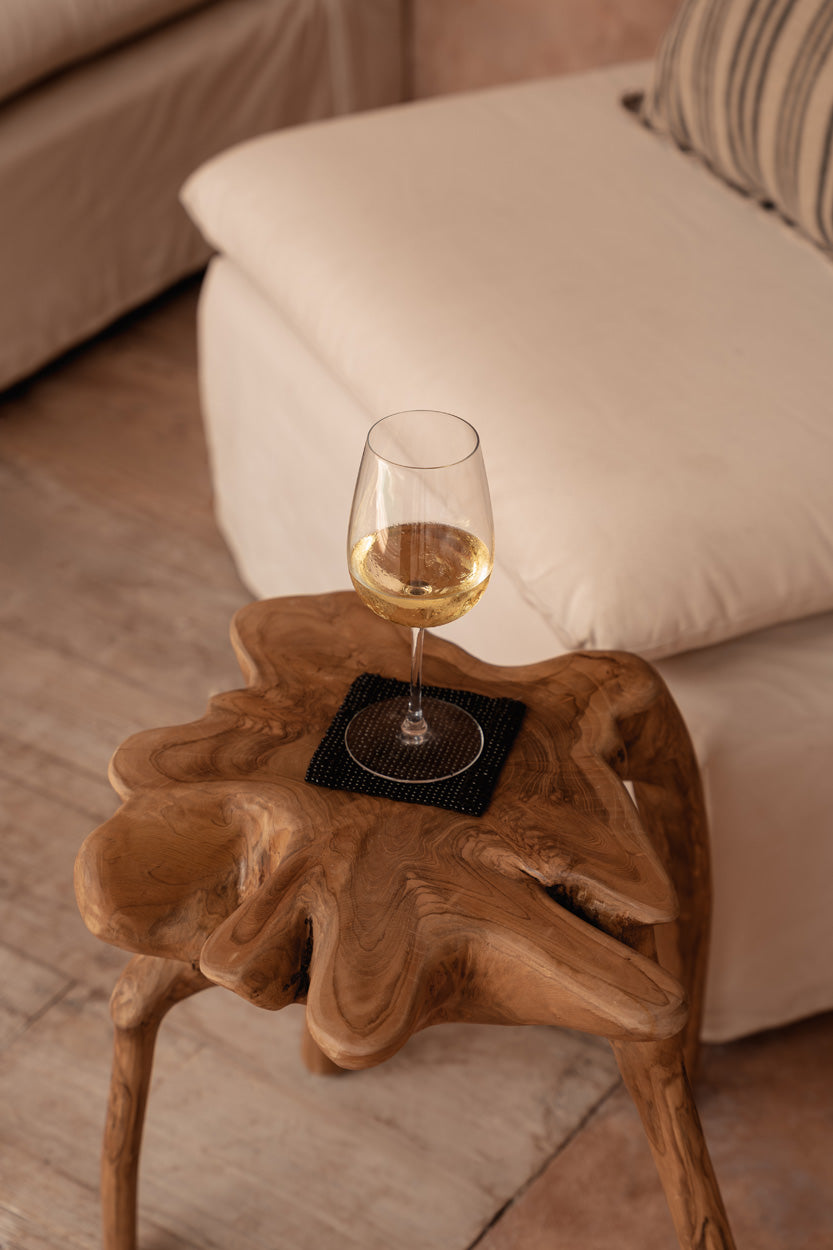 Wine glass on a wooden side table with a couch in the background