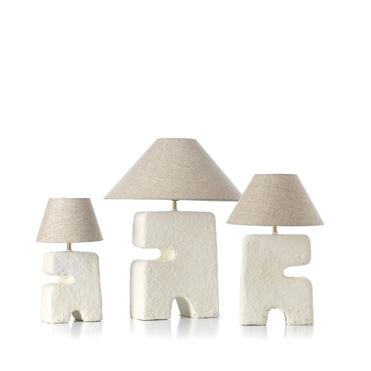 Three unique table lamps with geometric designs on a white background