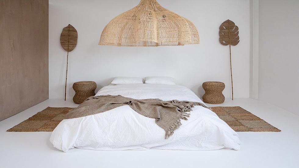 Oversized rattan ceiling light shade 150cm above a natural bedroom interior