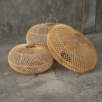 Three sizes of woven wicker rattan light shades  on a stone surface with a concrete wall background