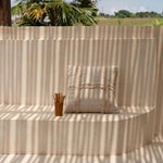 Beige cushion on a curved wall with palm trees and open field in the background