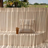 Beige cushion on a curved wall with palm trees and open field in the background