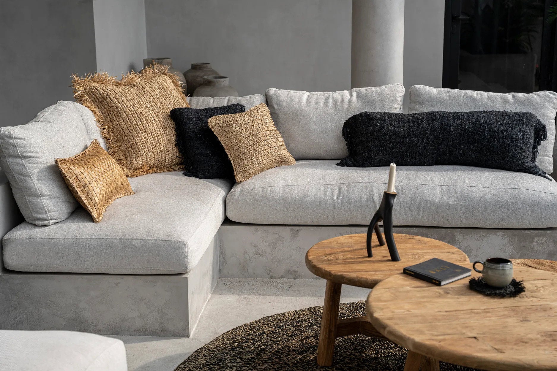 Gray sectional sofa with decorative wabi sabi cushion pillows in a modern living room setting.