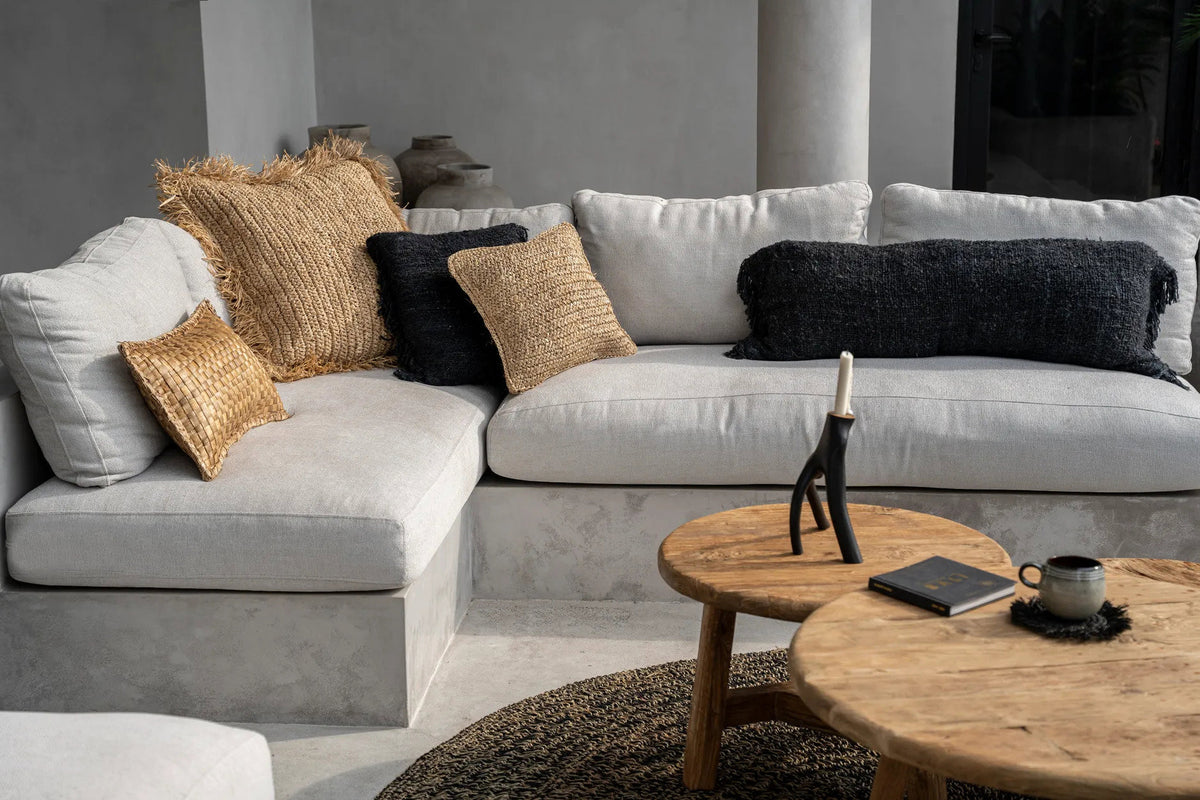Gray sectional sofa with decorative wabi sabi cushion pillows in a modern living room setting.