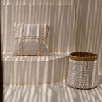 Textured pillow and basket on a striped wall with sunlight casting shadows