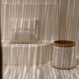 Textured pillow and basket on a striped wall with sunlight casting shadows