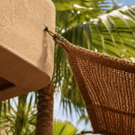 Hanging sunshade sail  attached to a wall with palm trees in the background