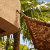 Hanging sunshade sail  attached to a wall with palm trees in the background