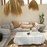 Modern living room with natural sofa, white coffee table, and raffia cushions and rug
.