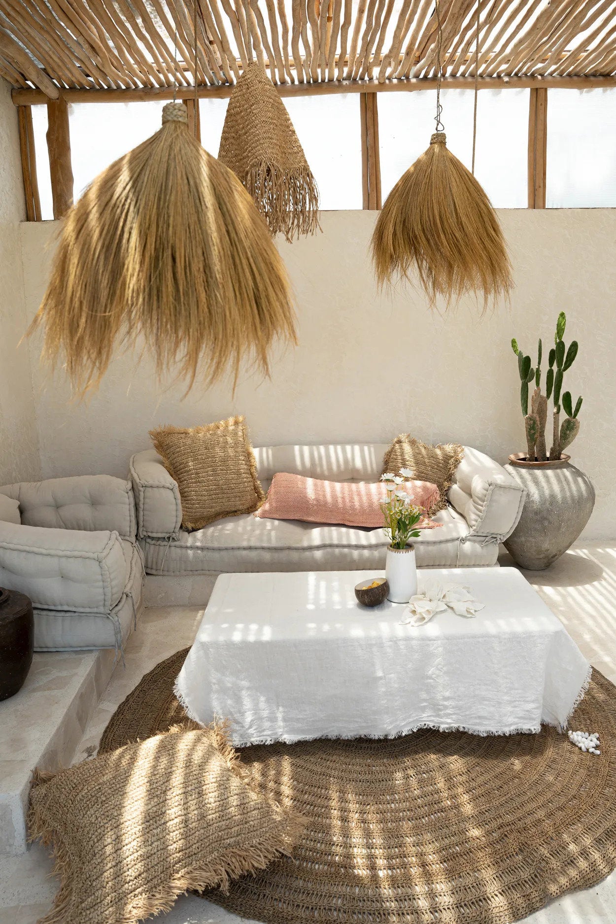 Modern living room with natural sofa, white coffee table, and raffia cushions and rug
.