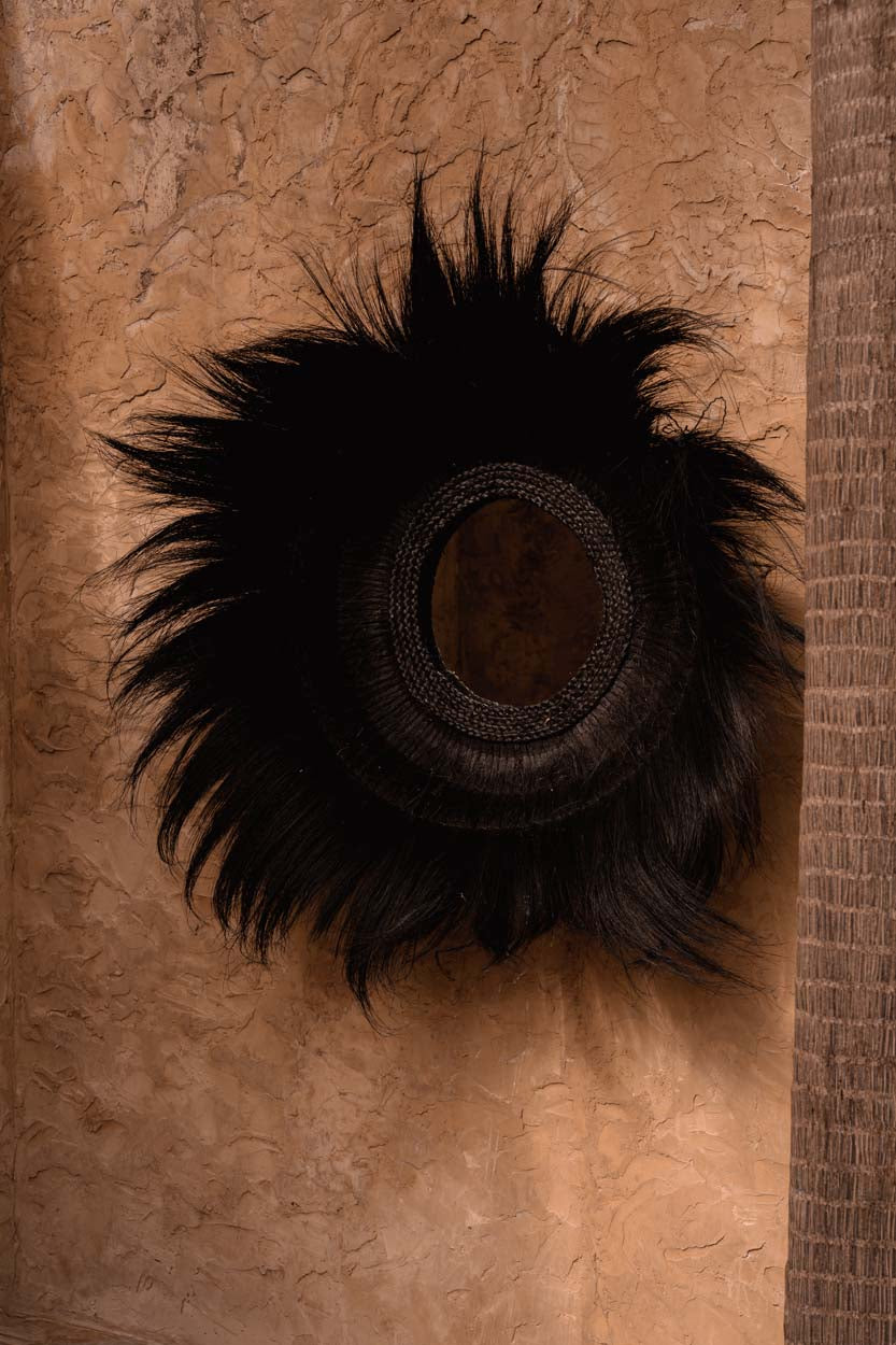 Decorative wall black grass mirror on a textured brown background