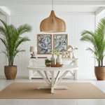 Modern living room with a  large rattan pendant light over a white table, plants, and decorative items.