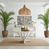 Modern living room with a  large rattan pendant light over a white table, plants, and decorative items.
