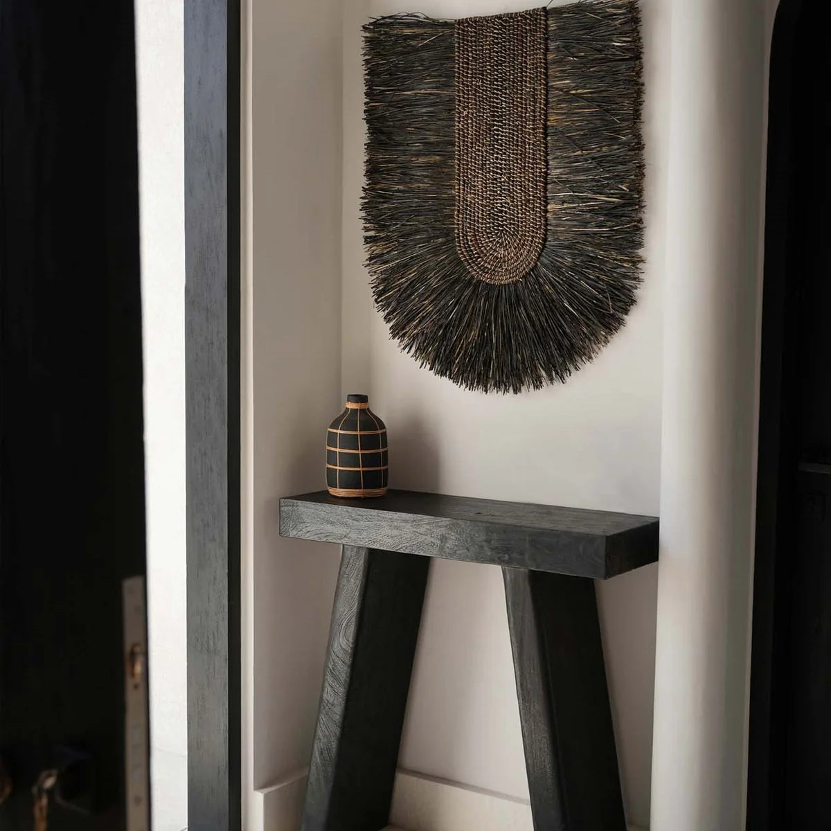 Black Wood Console table with black wall hanging in a limewash plastered room