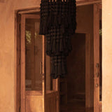 Black woven chandelier hanging in a room with wooden doors and beige walls.