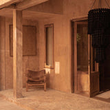 A rustic interior with a wooden chair and open door leading to a garden with extra large black chandelier