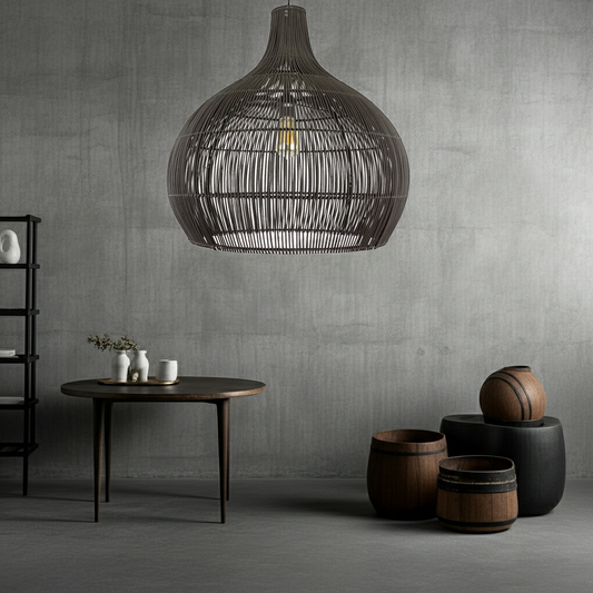 Modern interior with a large black rattan pendant light, table, and decorative items against a concrete wall.