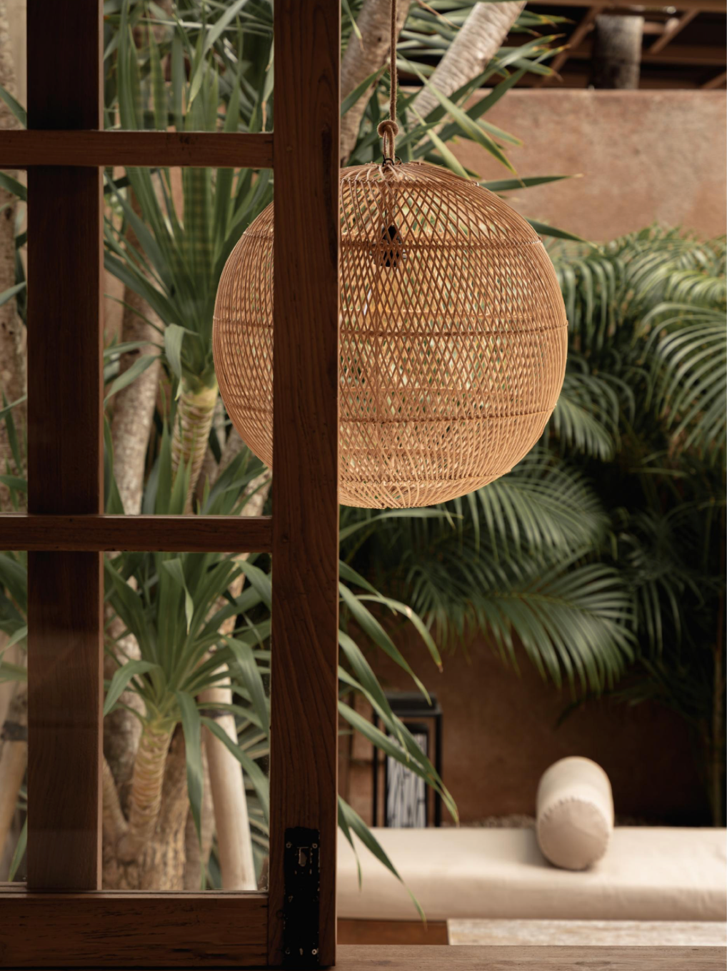 Large round woven rattan light lamp shade hanging in a conservatory