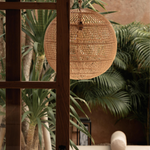 Large round woven rattan light lamp shade hanging in a conservatory
