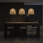 Modern kitchen island with three woven rattan pendant lights in a dark setting.