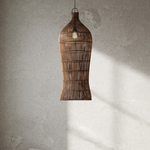 Rattan pendant light hanging in a room with a textured wall and window.