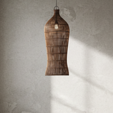 Rattan pendant light hanging in a room with a textured wall and window.