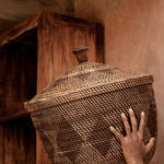 Person holding a woven basket above their head in a rustic setting