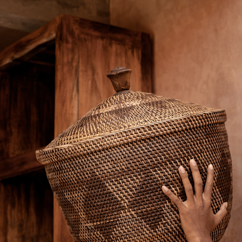 Person holding a woven basket above their head in a rustic setting
