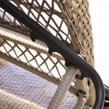 Close-up of a wicker outdoor lounger chair with black metal frame on a textured surface.