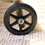 Close-up of a black wheel with metal hub of a Wicker rattan  sun lounger 
