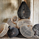 Collection of woven and textured rattan pendant lights  against a concrete wall.