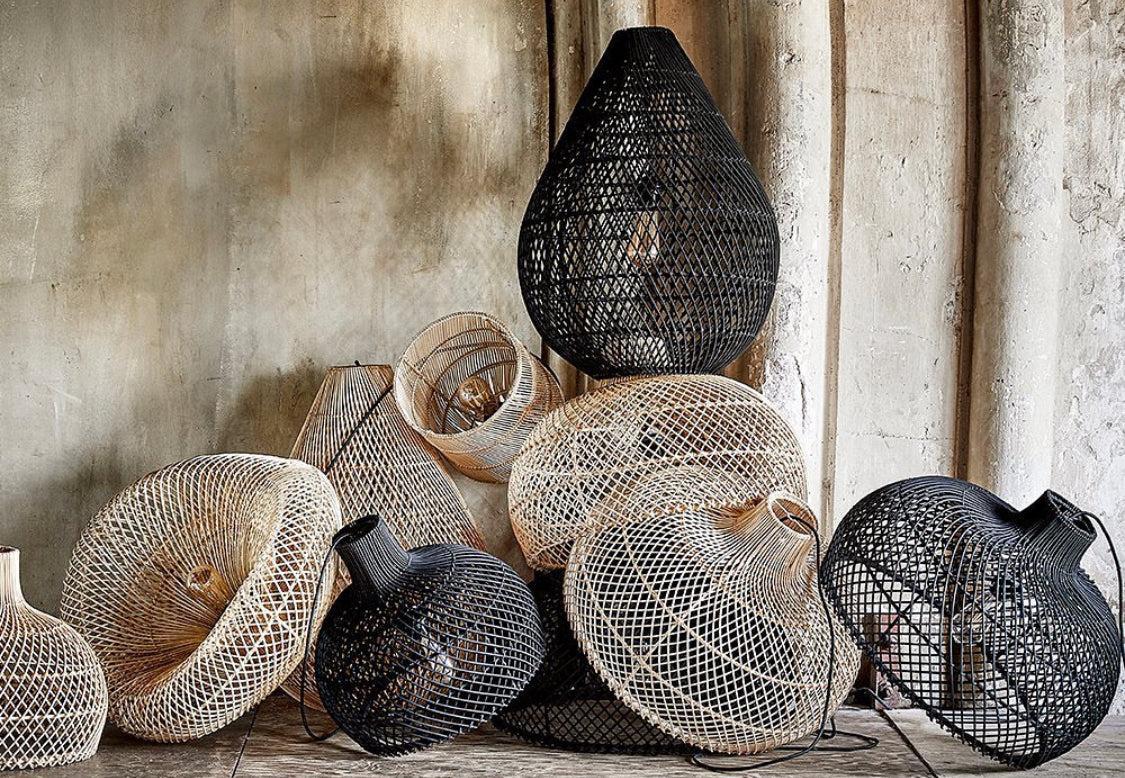 Collection of woven and textured rattan pendant lights  against a concrete wall.