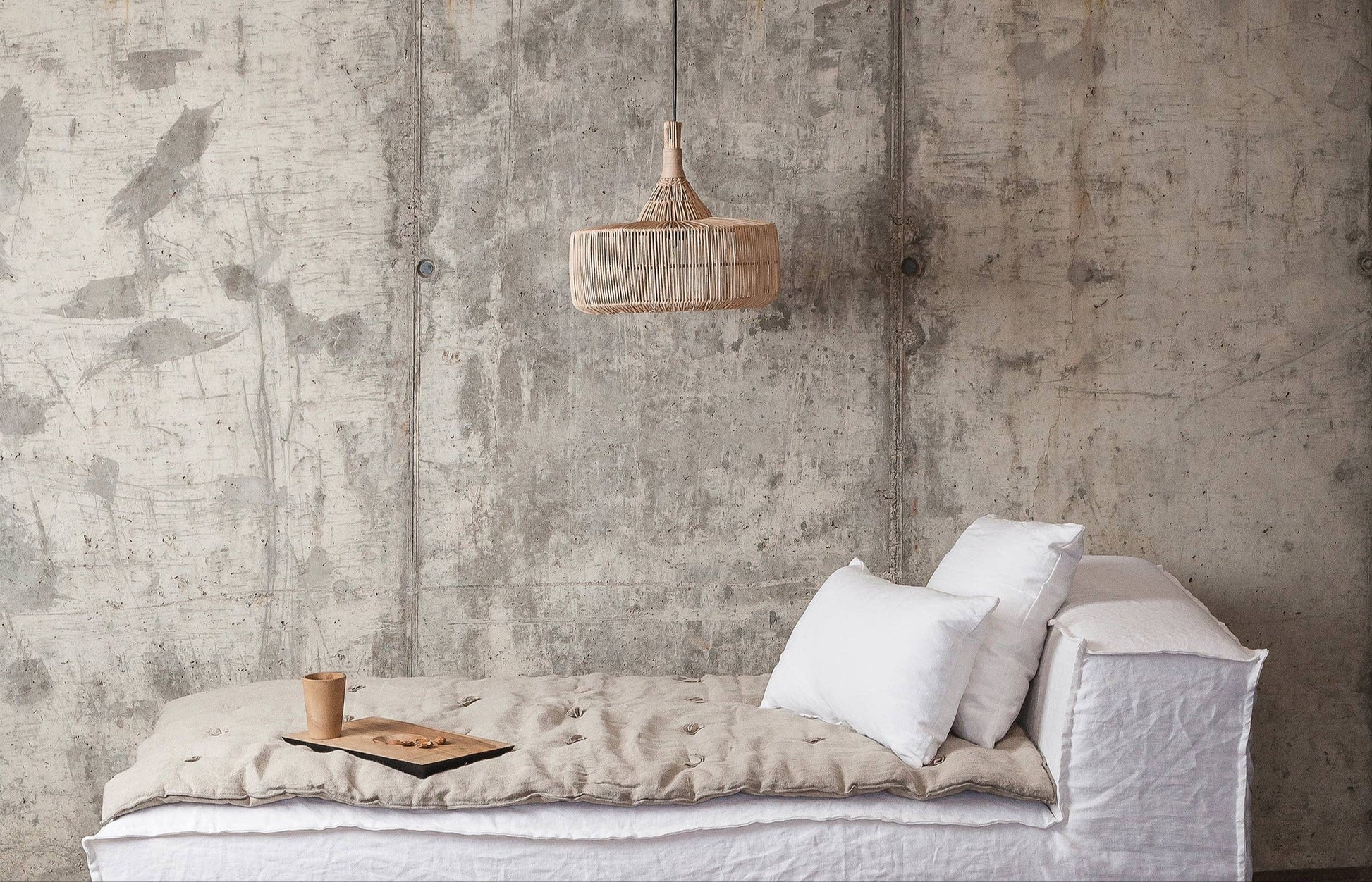 Minimalist interior with a white sofa against a textured concrete wall.