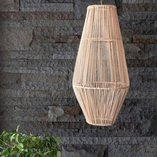 A natural woven rattan pendant light hangs against a dark gray stone wall, with green foliage visible in the lower left corner.