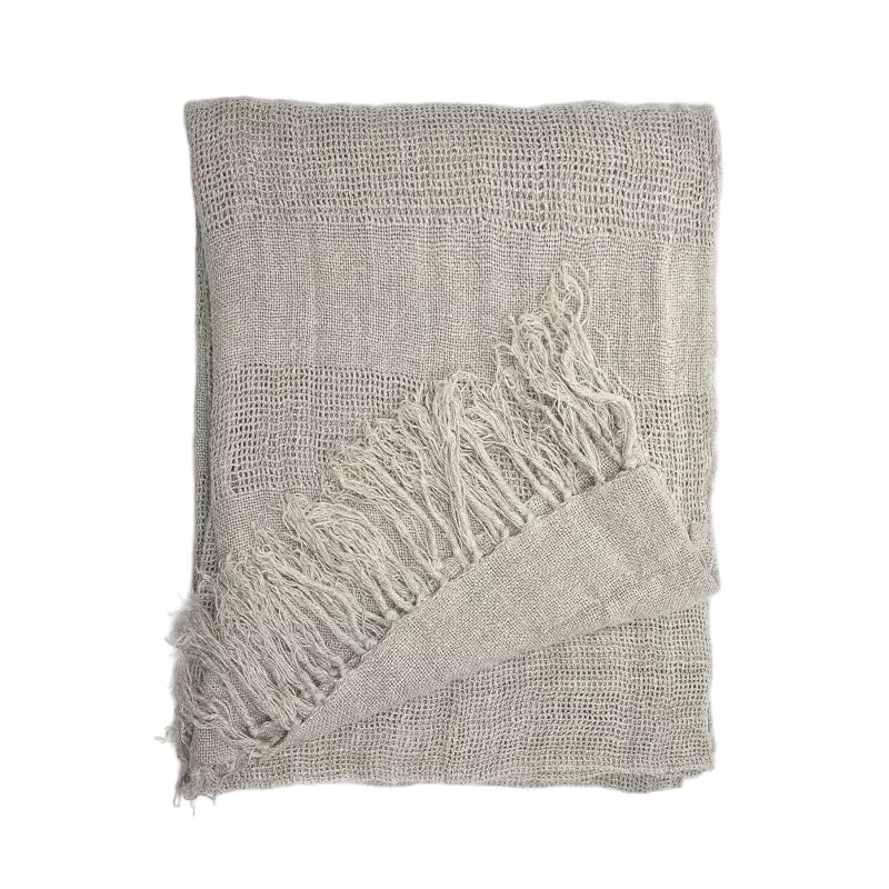 A folded linen curtain panelt in a light taupe-beige colour with fringed edges, displayed on a clean white background.