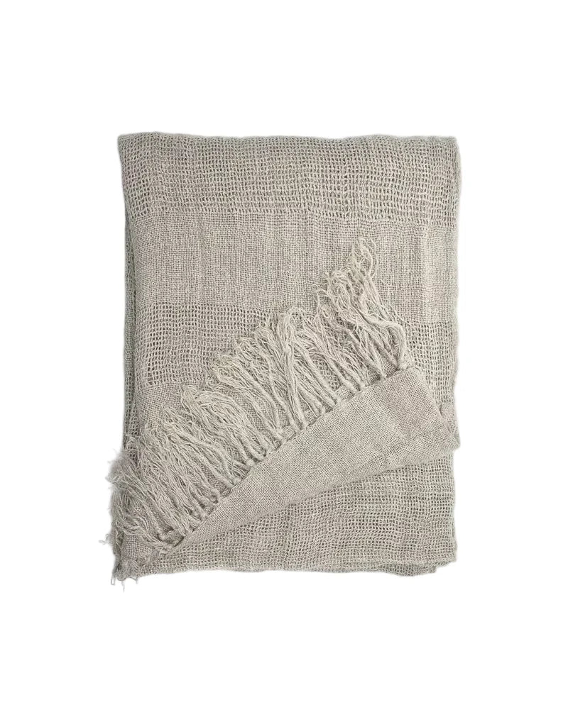 A folded linen curtain panelt in a light taupe-beige colour with fringed edges, displayed on a clean white background.