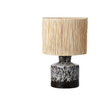 Table lamp with a textured beige shade and black and white ceramic base on a white background