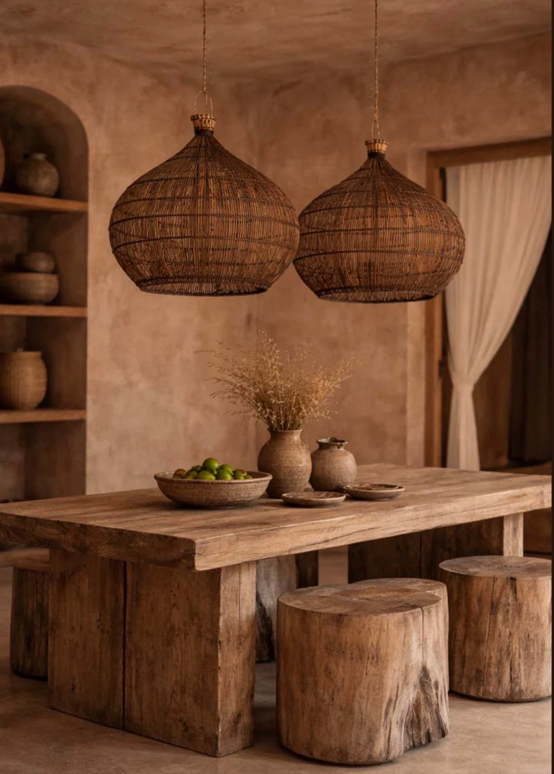 Kitchen dining area with wooden table, stools, and hanging woven rattan  light shades  in a warm toned room.