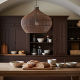 rattan ceiling lighjt in Kitchen with wooden table, bread, and bowls in a warm-toned room.