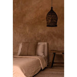 Bedroom with brown walls, bed, and dark rattan pendant light shade as bedside lamp
