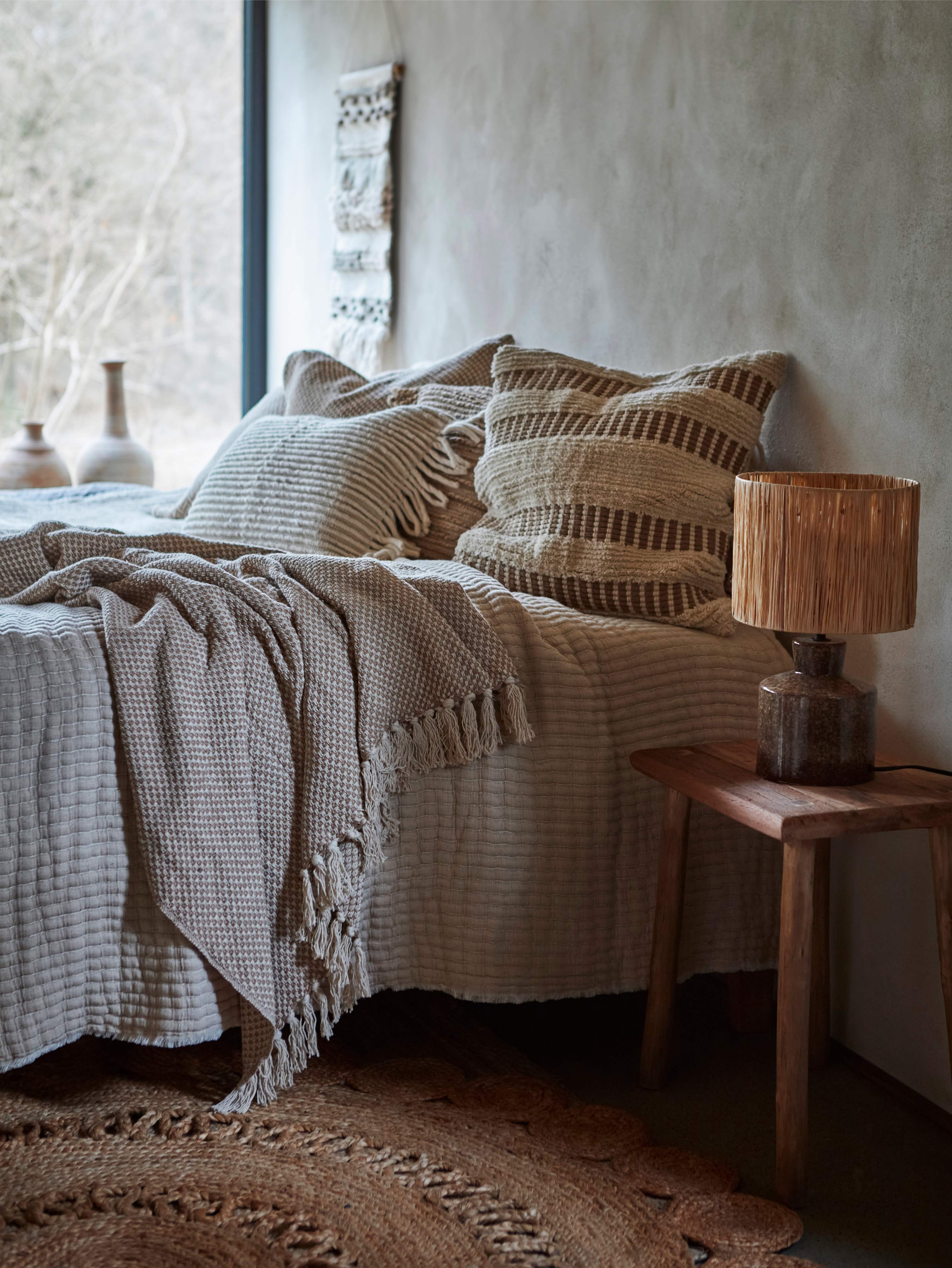 Cozs bedroom with textured bedding and stripe 50cm cushions, wooden nightstand with lamp 