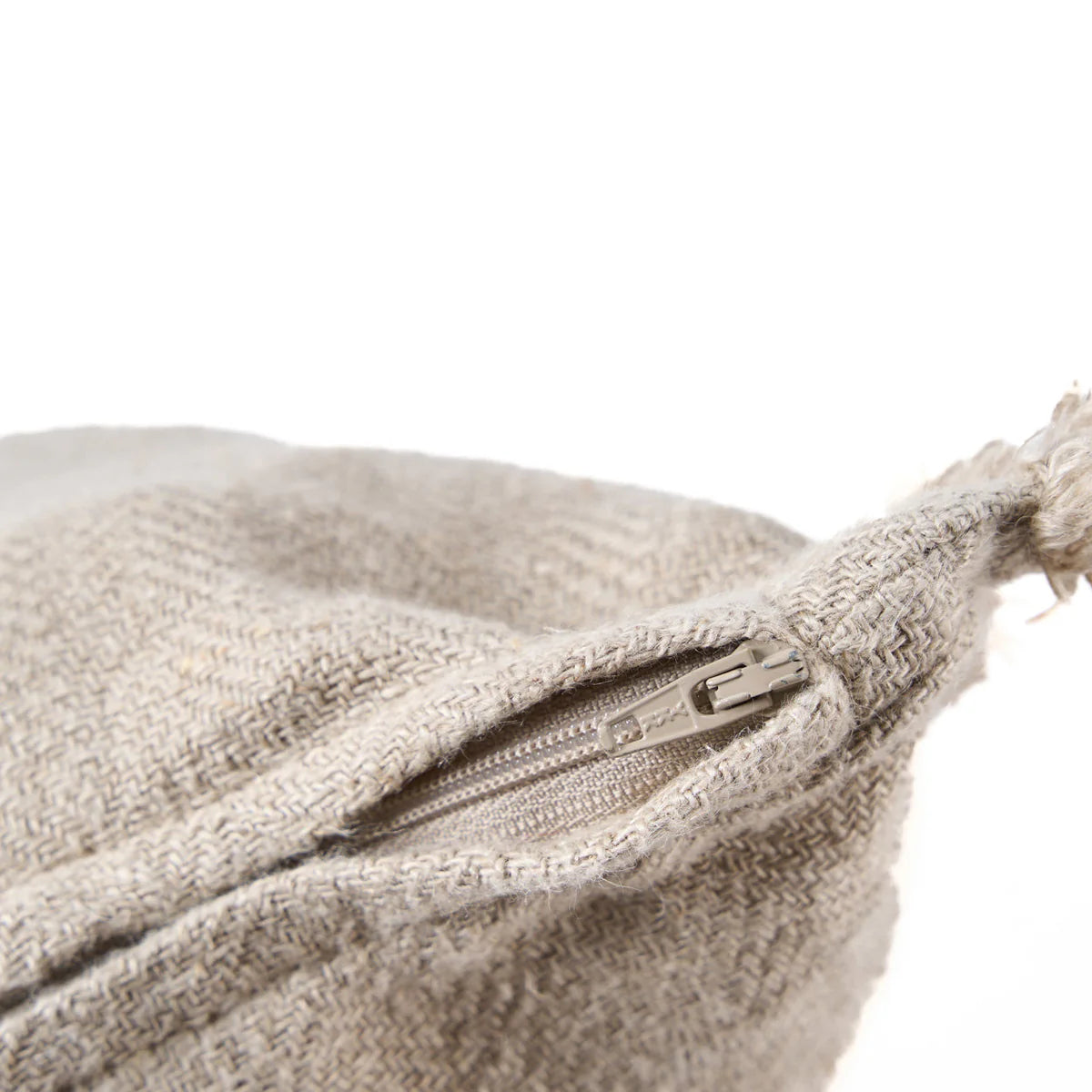Close up of a textured beige cushion zip with a zipper on a white background